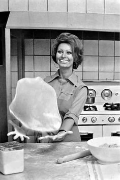 a woman in the kitchen is holding up a large cookie sheet and smiling at the camera