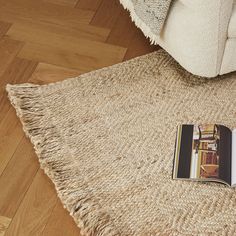 an open book sitting on top of a rug next to a white chair and wooden floor