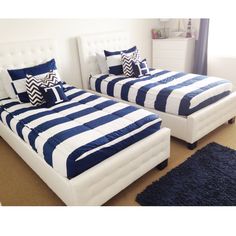 two beds with blue and white pillows in a room