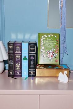 several books are sitting on a dresser with a swan figurine next to them