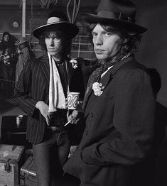 two men in suits and hats standing next to each other