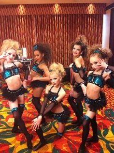 a group of women in costume posing for a photo on a carpeted room floor