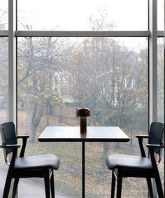 two chairs and a table in front of a large window with a view of trees outside