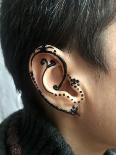 a person with black hair wearing a pair of ear piercings that are shaped like an octopus