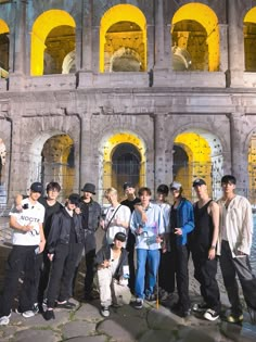 a group of young men standing next to each other in front of an old building