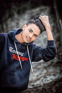 a young man in a black hoodie is posing for the camera with his hand on his head