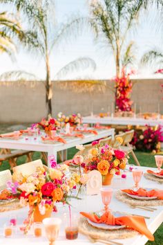 an outdoor table set up with flowers and place settings