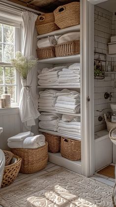 a white bathroom with lots of towels and baskets on the shelves in front of it