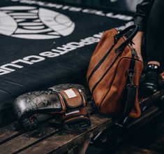 a brown bag sitting on top of a wooden bench next to a pair of boxing gloves