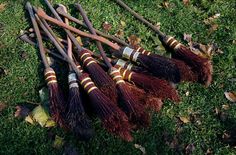 several brooms laying on the ground with their tops turned upside down and one lying in the grass