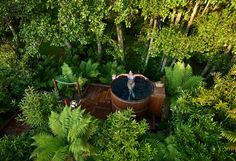 an aerial view of a person in a hot tub surrounded by trees and plants, with the water running through it