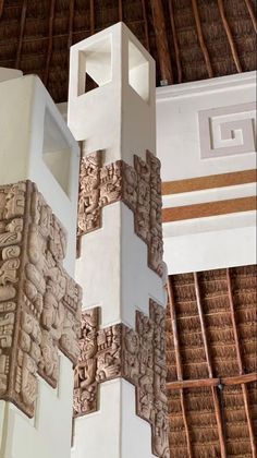 an intricately carved column stands in the middle of a room with thatched roof