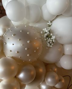 white balloons and flowers are arranged on the wall