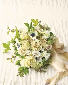 a bridal bouquet on a bed with white sheets