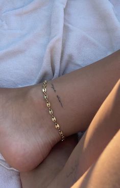 a close up of a person's foot with a gold chain on it