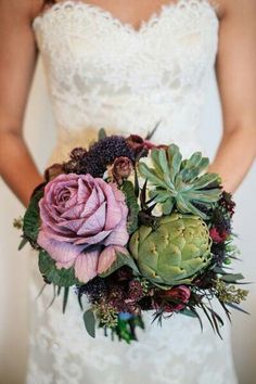 a bride holding a bouquet of flowers and succulents