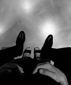 two people with their feet up in the air and one person wearing black dress shoes