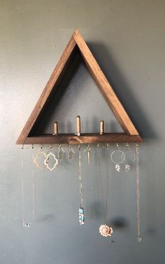 a wooden triangle hanging from the side of a wall with beads and chains attached to it