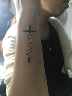 a woman with a cross tattoo on her arm and the word walk written in black ink