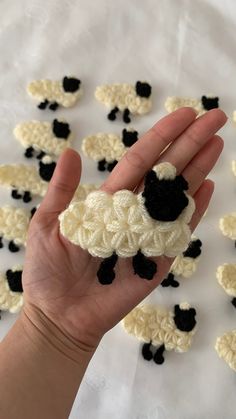 a hand holding a small crocheted black and white sheep