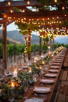 a long table is set with place settings and lit candles for an outdoor dinner party