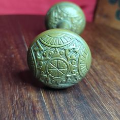 two green ceramic knobs sitting on top of a wooden table