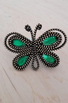 a green butterfly brooch sitting on top of a wooden table