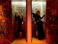 two women in urinals with graffiti on the walls