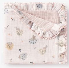 a pink blanket with animals on it and ruffles around the edges is laying on a white surface