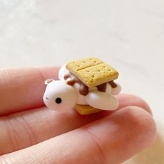 a tiny toy giraffe with a cracker on its head is held in someone's hand