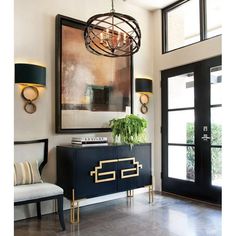 a living room with a large painting hanging on the wall next to a black cabinet