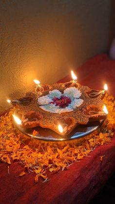 a plate that has some candles on it and flowers in the middle with one candle lit