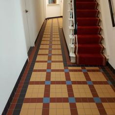 a long hallway with red carpeted stairs and tiled flooring on either side of the door