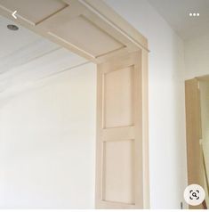 an open door in the middle of a room with white walls and wood trimmings