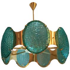 a green and gold chandelier hanging from a ceiling fixture with three circular glass shades