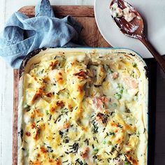 a casserole dish with meat and vegetables in it on a wooden cutting board