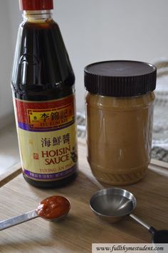 peanut butter, sauce and spoons on a wooden table next to a bottle of hoisin sauce