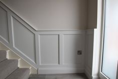 an empty room with white walls and gray carpeted stairs leading up to the second floor