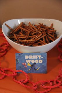 a white bowl filled with sticks on top of a table next to a red book