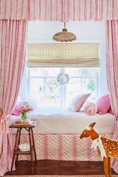 a pink and white bedroom with deer figurines on the floor, window curtained in