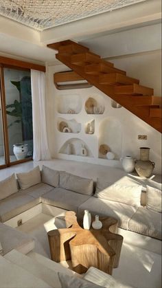 a living room filled with lots of furniture under a stair case next to a window