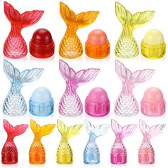 many different colored glass items in the shape of fish and mermaid tails on white background