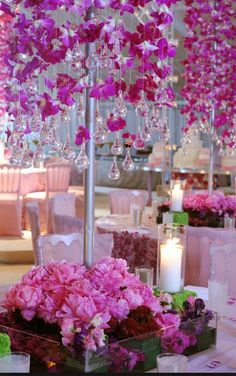 pink flowers and candles are on display in front of the tables at a wedding reception