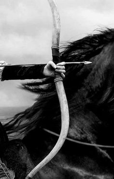 black and white photograph of a man on a horse with an arrow in his hand