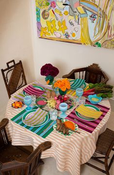 the table is set with colorful plates and flowers