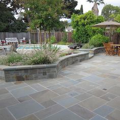 an outdoor patio with tables and chairs next to a swimming pool in the back yard