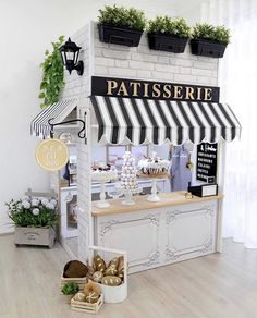 a pastry shop with white brick walls and black and white awning