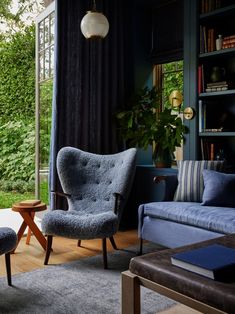 a living room filled with furniture next to a large open window covered in plants and greenery