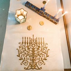 the table is set with candles and other items for hanukkah, including an embroidered menorah