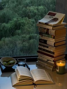 a stack of books sitting on top of a table next to a candle